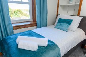 a bedroom with a bed with blue curtains and a window at Shell Cottage in Whithorn