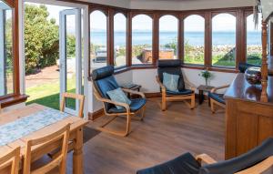 a living room with chairs and a table and windows at Shell Cottage in Whithorn