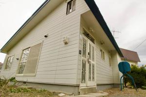 a white house with a large door at Hokkaido Wander House in Ashibetsu