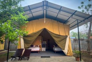 a tent with a bed and two chairs in it at Hotel Tharu Garden in Sauraha