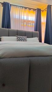 a large bed with blue curtains in a bedroom at Vito Haven suites in Busia