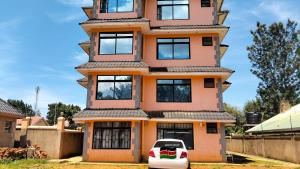 a white car parked in front of a tall building at Vito Haven suites in Busia