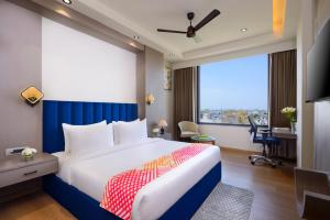 a bedroom with a bed and a desk and a window at Ginger Kota, Vishwakarma Nagar in Kota