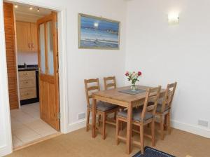 a dining room with a wooden table and chairs at Mulberry Cottage in Whithorn