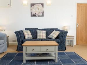 a living room with a blue couch and a table at Mulberry Cottage in Whithorn