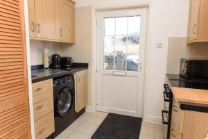 a kitchen with a washing machine and a window at Mulberry Cottage in Whithorn