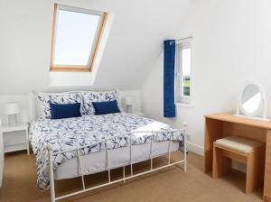 a bedroom with a bed with blue pillows and a mirror at Mulberry Cottage in Whithorn +1 photo