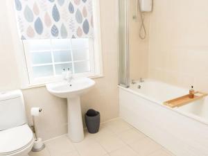 a bathroom with a sink and a toilet and a window at Mulberry Cottage in Whithorn