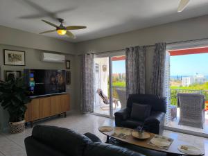 a living room with a couch and a tv at Villa Best Holiday Sea View Private Pool near Coral Bay with Garden and BBQ in Peyia
