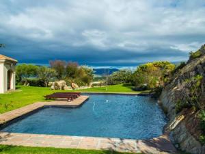 a swimming pool with benches next to a stone wall at Barton Luxury Villas in Hermanus