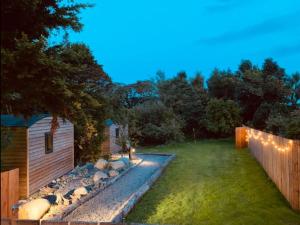 a backyard with a fence and a garden with lights at Ivy in Whithorn +3 photos