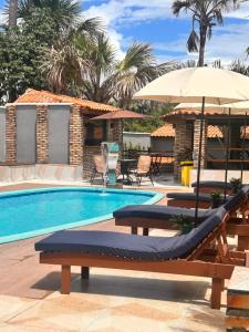 a swimming pool with two lounge chairs and an umbrella at Pousada Luz do El Shaday in Barreirinhas