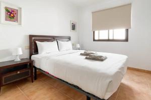 a bedroom with a large white bed and a window at Lamar Suites in Arinaga