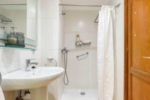 a white bathroom with a sink and a shower at Lamar Suites in Arinaga