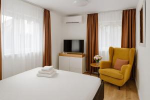 a bedroom with a bed and a chair and a television at Cazare Colibita - Casa Lipan cu jacuzzi, foișor și loc de joacă in Colibiţa