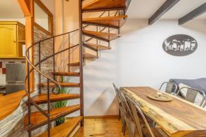 a spiral staircase in a dining room with a wooden table at Dúplex acogedor en La Molina- 8 Pax in La Molina