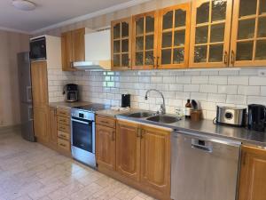 a kitchen with wooden cabinets and stainless steel appliances at Aspa Herrgård - Handelshuset in Askersund +25 photos