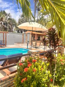 a swimming pool with an umbrella and some flowers at Pousada Luz do El Shaday in Barreirinhas