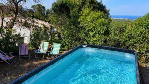 a swimming pool with two lawn chairs at Piscine & Vue Mer, Maison Familiale Corse, accès cascade in Santa-Maria-Poggio