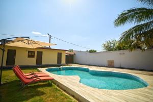 a swimming pool with a red chair and a house at La Samurai House Assinie in Assinie