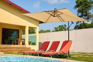 a group of chairs and an umbrella next to a pool at La Samurai House Assinie in Assinie