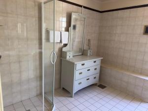 a bathroom with a shower and a dresser with a mirror at Aspa Herrgård - Handelshuset in Askersund