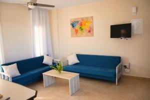 a living room with a blue couch and a tv at Proteas Mare Suites in Protaras