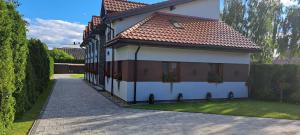 a white house with a red roof and some plants at Pod Dachem Tykocin in Tykocin