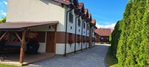 a building with a walkway next to a hedge at Pod Dachem Tykocin in Tykocin