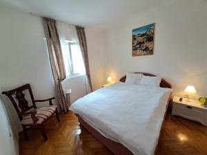 a bedroom with a large white bed and a chair at House Leana Herceg Novi in Herceg-Novi
