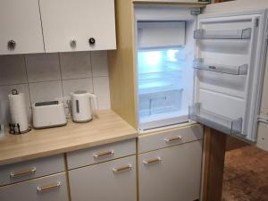 an empty refrigerator with its door open in a kitchen at NEU! Ferienwohnung Gondwana in Schiffweiler