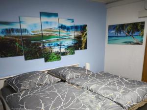 a bedroom with a bed with four paintings on the wall at NEU! Ferienwohnung Gondwana in Schiffweiler