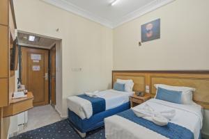 a hotel room with two beds and a television at Wahet Al Deafah Hotel in Mecca +1 photo