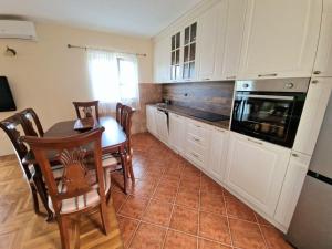 a kitchen with white cabinets and a table and chairs at House Leana Herceg Novi in Herceg-Novi +19 photos