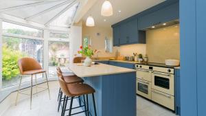 a kitchen with blue cabinets and a table with stools at Number eight in Beaumaris