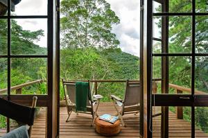 a porch with chairs and a view of a forest at Casa da Colina Chalés in Visconde De Maua