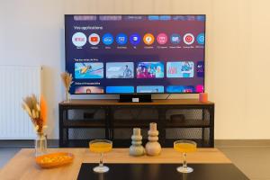 a television with two wine glasses on a table at T3 moderne- Climatisé avec Parking & Terrasse à 5 min de Montpellier in Saint-Jean-de-Védas