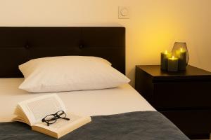 a bed with a book and a pair of glasses on it at T3 moderne- Climatisé avec Parking & Terrasse à 5 min de Montpellier in Saint-Jean-de-Védas