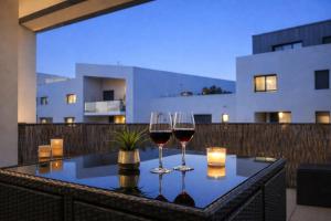 two glasses of wine sitting on a table on a balcony at T3 moderne- Climatisé avec Parking & Terrasse à 5 min de Montpellier in Saint-Jean-de-Védas +9 photos