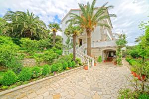 a house with palm trees and a walkway at App&Rooms Anica Kampor in Kampor