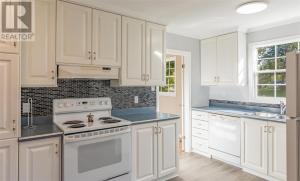 a kitchen with white cabinets and white appliances at St Andrews Guest Home in St. John's