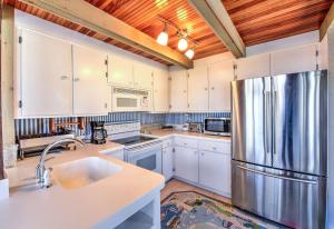 a kitchen with white cabinets and a stainless steel refrigerator at Sun Serenity at A Wave From It All in Pocasset