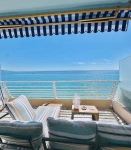 a balcony with a couch and chairs and the ocean at Casa Sud Menton vue mer exceptionnelle terrasse parking inclus climatisation in Menton
