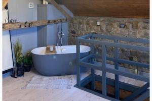 a bathroom with a blue tub and a stone wall at The Stable Sleeps 2 with Parking in Llanfairpwllgwyngyll +2 photos