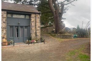 a stone house with a blue garage at The Stable Sleeps 2 with Parking in Llanfairpwllgwyngyll