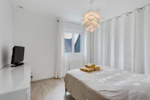 a white bedroom with a bed and a television at Macleo proche plage in Plougasnou