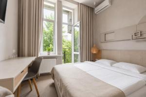 a bedroom with a bed and a desk and a window at Poet Art Hotel in Odesa