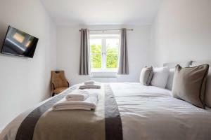 a large white bed in a room with a window at Cheltenham Cottage in Cirencester