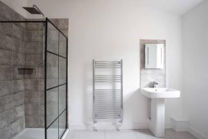 a white bathroom with a sink and a shower at Cheltenham Cottage in Cirencester