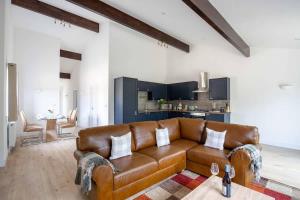 a living room with a brown couch and a kitchen at Cheltenham Cottage in Cirencester